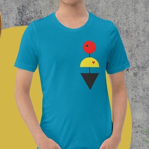 Könnte beinhalten: Ein türkisfarbenes T-Shirt mit einem geometrischen Design, das einen roten Kreis, einen gelben Kreis und ein schwarzes Dreieck zeigt.