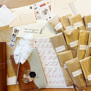 May include: A calligraphy kit with a range of supplies, including a quill pen, ink, and paper. The kit also features a set of envelopes and a notebook with the words "The cursive connection" on the cover.