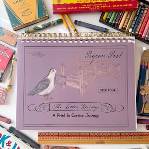 May include: A spiral-bound workbook titled Pigeon Post: The Letter Bridge, A Print to Cursive Journey, featuring a drawing of a pigeon with an envelope and a wooden bridge. A wooden ruler measuring 10.5 inches is placed below the workbook.