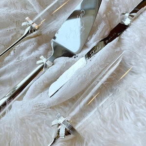 May include: A silver wedding cake knife and two champagne flutes with engraved bows and the text "Emily & Jesse 10.26.23" and "Love Field Forever & Always" on the knife and "Love Field Forever & Always  & Me" on the flute.