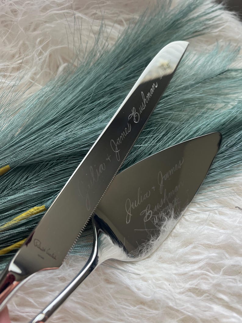 May include: A silver wedding cake knife and server set with the inscription "Julia + James Bushman 11.13.2022" engraved on the blades.