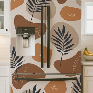 May include: A double-door refrigerator featuring a light beige background with a repeating pattern of dark navy blue palm leaf silhouettes and irregular organic shapes in shades of terracotta, tan, and brown, including a built-in water dispenser.