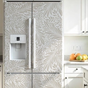 May include: A white refrigerator with a light gray floral pattern. The refrigerator has a water dispenser and is surrounded by white cabinets and a countertop. The kitchen has a bright and airy feel.