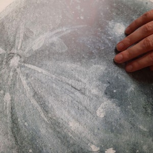 Pu&ograve; includere: Primo piano di un ornamento grigio e bianco testurizzato con un motivo a fiocco di neve. L'ornamento &egrave; leggermente sfocato.