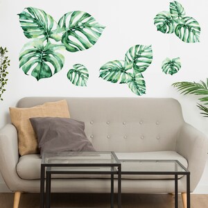 You can see that monstera wall decal set make living room jungle theme decorated. Large Watercolor Monstera Wall Decals, Monstera leaf, Tropic leaves decal, Tropical plants decal. The photo describe large watercolor monstera wall decals above sofa.
