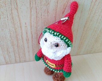 May include: A handmade crochet Santa Claus ornament. The Santa figure is dressed in a red suit with green and white accents, a white beard, and a red hat. The ornament has brown shoes and a gold belt.