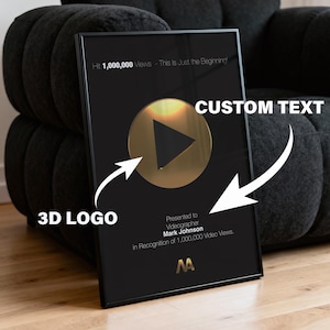 Könnte beinhalten: Schwarze Auszeichnungstafel mit goldenem Play-Button und dem Text "Hit 1,000,000 Views - This is Just the Beginning!". Die Tafel wird Mark Johnson in Anerkennung von 1.000.000 Videoaufrufen überreicht.