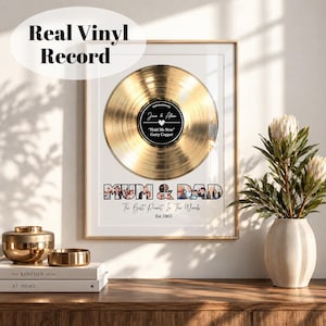 Könnte beinhalten: Ein gerahmtes Wandbild mit einer goldenen Schallplatte und einem schwarzen Mittellabel mit der Aufschrift "Gold Anniversary", "Jane & Alan" und "Hold Me Now". Unter der Platte enthält der Text "MUM & DAD" kleine Fotos, gefolgt von "The Best Parent In The World" und "Est 1963".