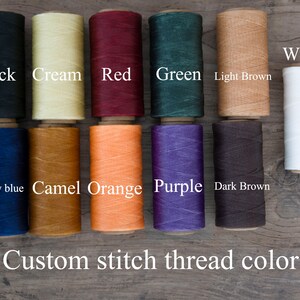 May include: A selection of colorful spools of thread in various shades, including black, cream, red, green, light brown, white, roay blue, camel orange, purple, and dark brown. The text "Custom stitch thread color" is displayed below the spools.