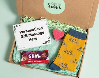 May include: A brown cardboard gift box containing a pair of mustard yellow socks with a navy blue bicycle pattern, a Gnaw milk chocolate bar, a pink heart-shaped object, and a white card with the text Personalised Gift Message Here.