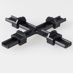May include: Black plastic connector for joining four pieces of track lighting together. The connector has four slots for track lighting and a central hub.