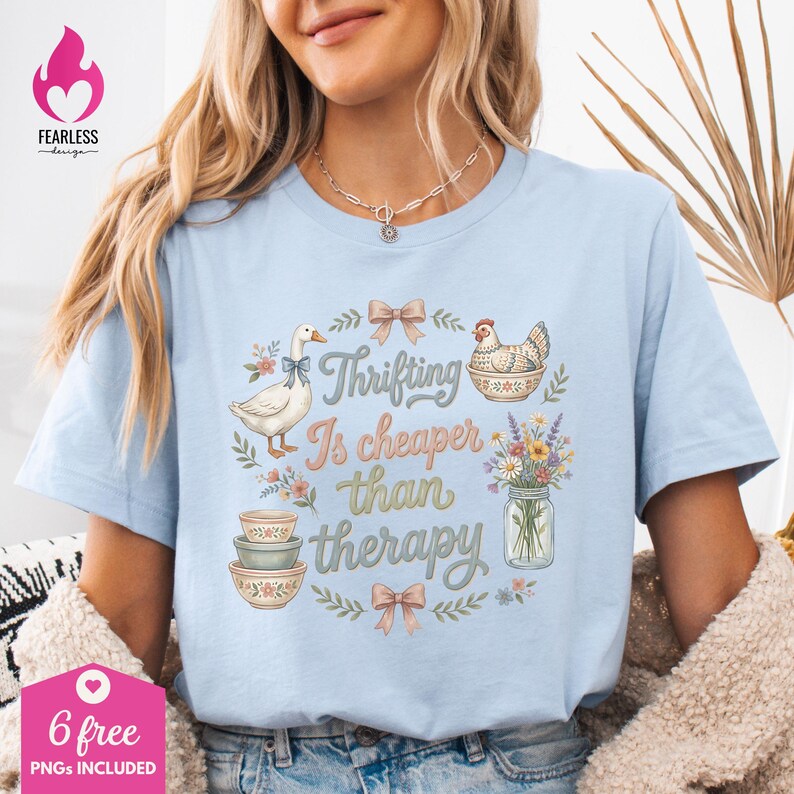 Puede incluir: Camiseta azul claro con el texto "Thrifting Is cheaper than therapy" en una fuente caprichosa. El dise&ntilde;o incluye ilustraciones de un ganso, una gallina, cuencos, flores y lazos. La camiseta tambi&eacute;n tiene el texto "6 free PNGs included".