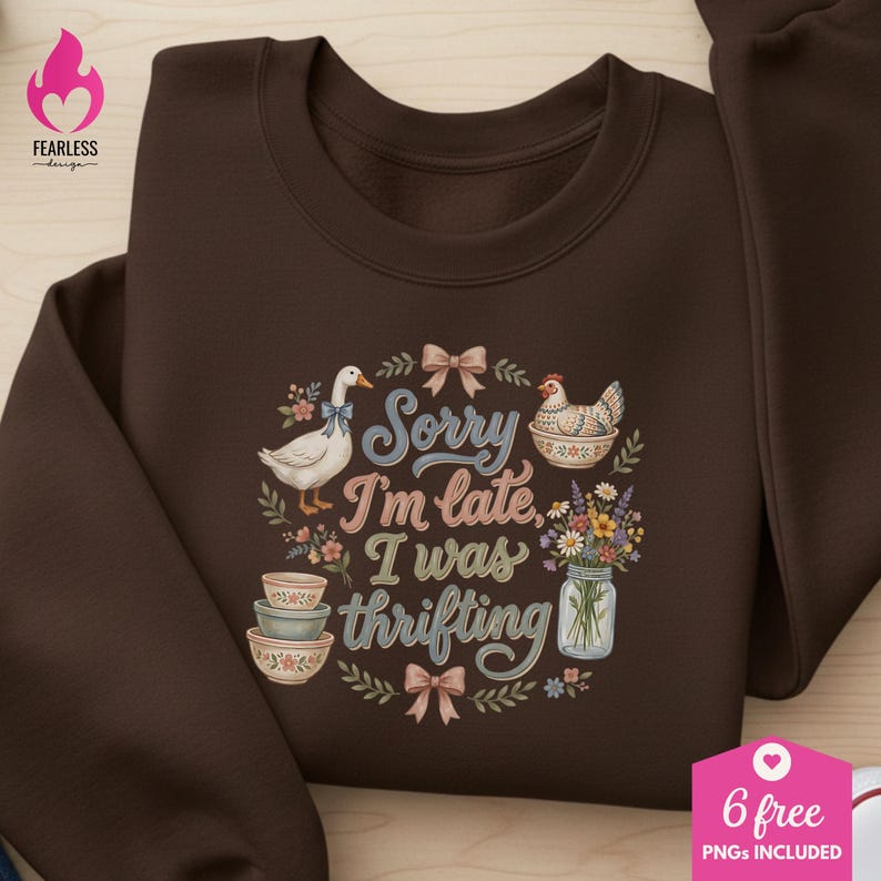 May include: A brown sweatshirt with a whimsical design. The design includes a goose, a chicken, floral elements, and the text "Sorry I'm late, I was thrifting." The sweatshirt has a crew neck and long sleeves.