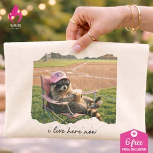 Può includere: Tela color crema con un procione con occhiali da sole e un cappello rosa con la scritta "Softball Mum", che si rilassa su una sedia pieghevole con una bevanda. L'immagine ha il testo "i live here now" e un'etichetta rosa a forma di cuore con "6 free PNGs included".
