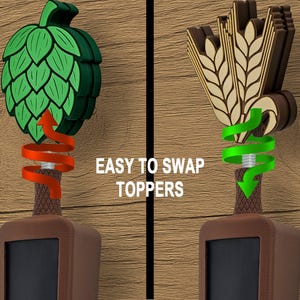 May include: Two beer tap handles with interchangeable toppers. One features a green hop design, the other a wheat and barrel design. The text "EASY TO SWAP TOPPERS" is displayed on a wooden background.