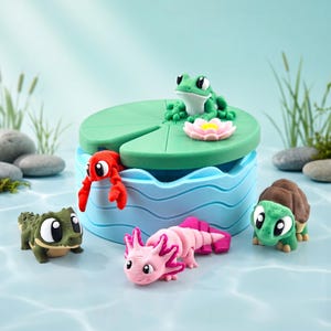 Puede incluir: Un juego temático acuático caprichoso con una rana verde, un cangrejo rojo, un ajolote rosa, una tortuga verde y un caimán verde. El juego incluye una base azul con forma de agua y una hoja de nenúfar verde con una flor rosa.
