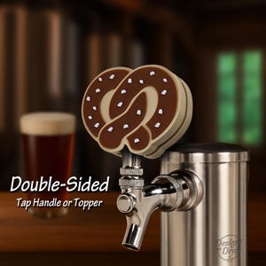 May include: A double-sided tap handle or topper with a pretzel design. The pretzel is brown with white accents and is mounted on a stainless steel tap. The text "Double-Sided Tap Handle or Topper" is visible.