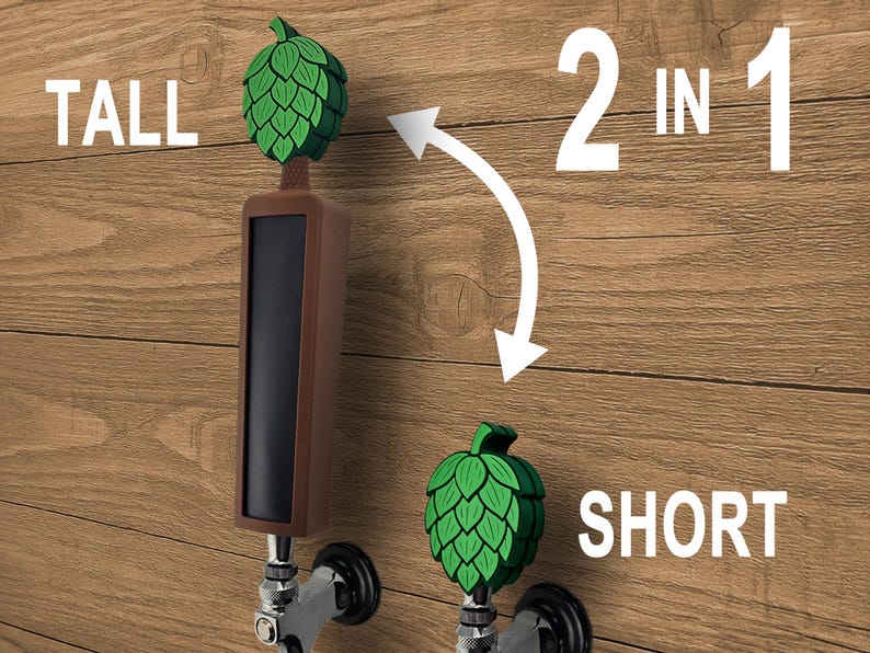 May include: A brown and black tap handle with a green hop design. The image shows two tap handles, one tall and one short, with the text "2 in 1". The word "TALL" is above the tall handle, and "SHORT" is below the short handle.