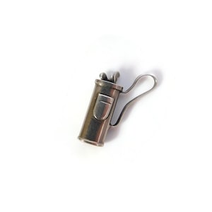 May include: A silver-toned metal charm shaped like a golf bag. The charm features a cylindrical body with a small rectangular pocket detail on the front, a curved handle extending from the side, and small club heads visible at the top opening.