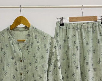 May include: A green pajama set with a button-up top and pants. The fabric has a small floral print.