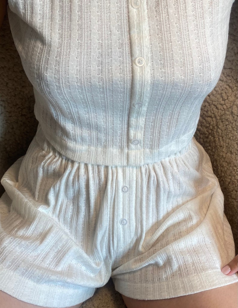 May include: White ribbed knit short set with a button-up top and matching shorts. The set has a relaxed fit and is made of a soft, comfortable fabric.