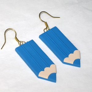 May include: A pair of blue pencil-shaped earrings with a white eraser detail. The earrings have gold hooks.