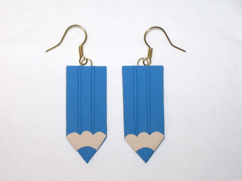 May include: A pair of blue pencil-shaped earrings with a white eraser detail. The earrings have gold hooks.