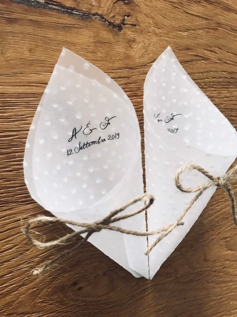 May include: Two white paper cones with a dotted pattern and tied with twine. The cones are decorated with black calligraphy that reads "A & F 12 Settembre 2019".