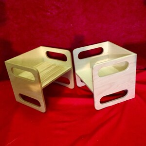 May include: Two wooden step stools with rounded edges and open sides. The stools are made of light wood and have a natural finish.