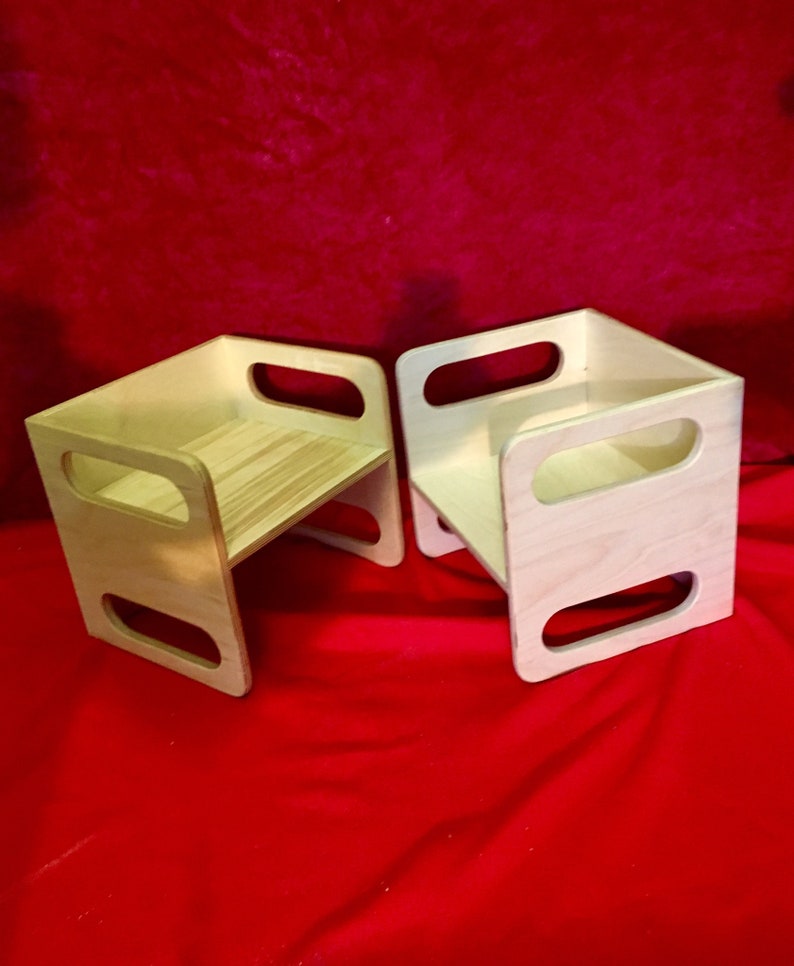 May include: Two wooden step stools with rounded edges and open sides. The stools are made of light wood and have a natural finish.