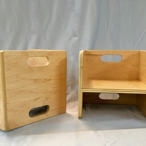 May include: Two wooden step stools with cut-out handles. The stools are made of light wood and are in a folded position.