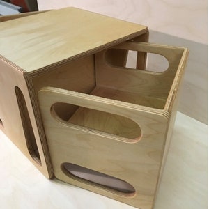 May include: A wooden box with a lid that opens to reveal a smaller box inside. The smaller box has two oval cutouts on the front.