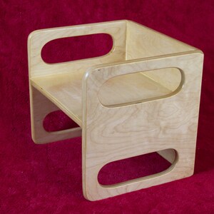 May include: A wooden step stool with rounded edges and three oval cutouts. The stool is made of light wood with a natural finish.