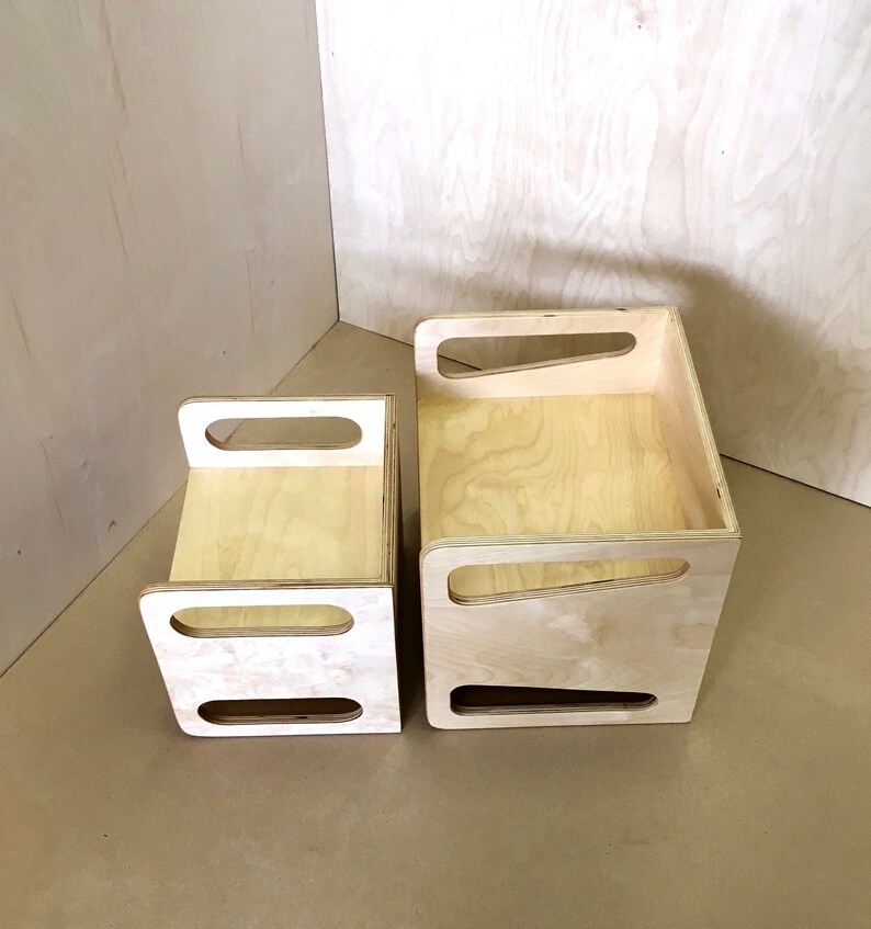 May include: Two unfinished wooden storage boxes of different sizes. Each box has a rectangular shape with cut-out handles on the sides. The wood grain is visible, and the boxes are set against a light-colored background.