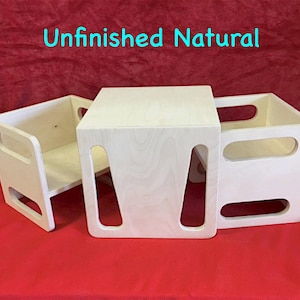 May include: Unfinished natural wood children's furniture set, including a small chair and a cube-shaped table or storage unit. The chair has a back and armrests. The table has cut-out handles. The text "Unfinished Natural" is visible.