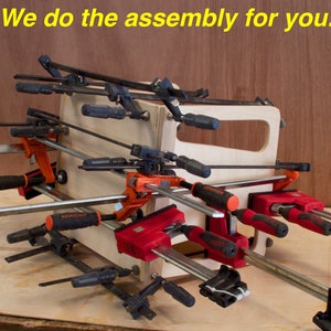 May include: A wooden box held together with various clamps. The clamps are black, red, and orange with silver bars. The text "We do the assembly for you" is in yellow at the top of the image.