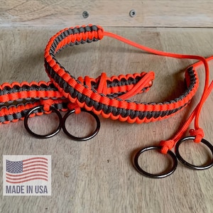 May include: Two black and orange paracord lanyards with metal rings. The lanyards are braided and have a contrasting color pattern. The text "MADE IN USA" is visible in the image.