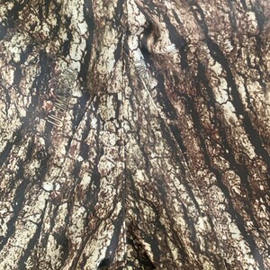 May include: Close-up of a brown and tan camouflage fabric with the text "ULTIMATE CAMO" printed on the left side and "CAMO" printed on the right side.