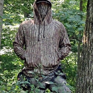 May include: A brown and tan camouflage hoodie with a drawstring hood. The hoodie is made of a soft, comfortable material and features a realistic tree bark pattern.