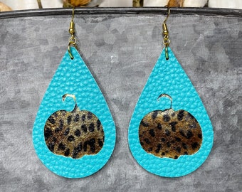 May include: Teal blue leather teardrop earrings with a gold-toned metal hook and a cutout of a leopard print pumpkin.