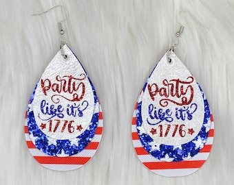 May include: A pair of red, white, and blue dangle earrings with the text "Party like it's 1776" on the front. The earrings are made of faux leather and have a glitter finish.
