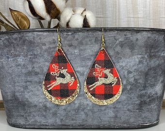 May include: A pair of red and black plaid teardrop-shaped earrings with gold glitter trim and a gold reindeer silhouette.
