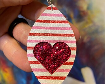 May include: Red and white striped dangle earrings with a pink glitter heart in the center.