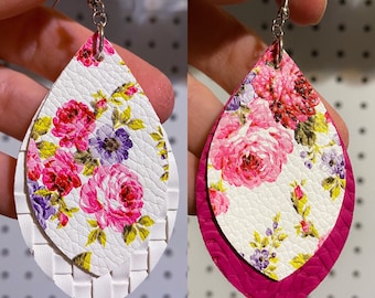 May include: A pair of white and pink floral dangle earrings with a white woven pattern on the top layer and a solid pink layer on the bottom.