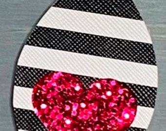 May include: Black and white striped dangle earrings with a pink glitter heart in the center.