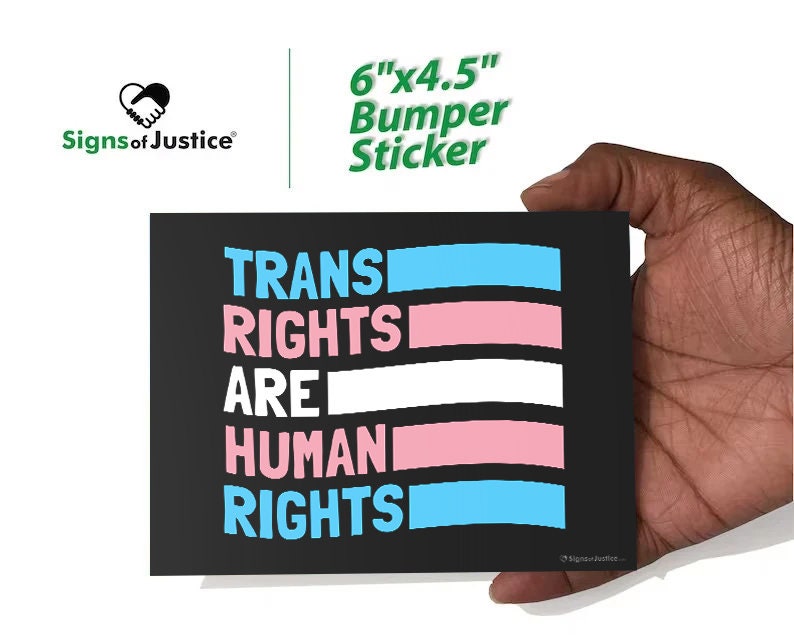 May include: A black bumper sticker with the text "TRANS RIGHTS ARE HUMAN RIGHTS" in white, pink, and blue. The sticker is 6" x 4.5" and features the "Signs of Justice" logo. The design incorporates the colors of the transgender pride flag.