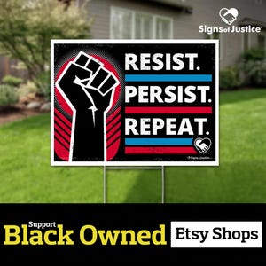 May include: Black and white yard sign with a raised fist and the text "Resist. Persist. Repeat." in red, white, and blue. The sign is on a wooden stake and is in front of a green lawn.