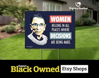 May include: A blue and white yard sign with a portrait of Ruth Bader Ginsburg and the text "Women belong in all places where decisions are being made." The sign is from Signs of Justice.