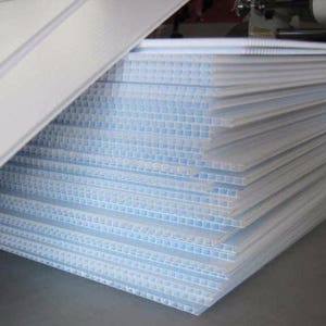 May include: A stack of white corrugated plastic sheets. The sheets are translucent and have a grid pattern.