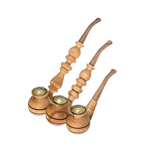 Puede incluir: Tres pipas de fumar de madera con detalles decorativos. Las pipas están dispuestas en forma de triángulo, con la pipa más grande en la parte inferior y la más pequeña en la parte superior.